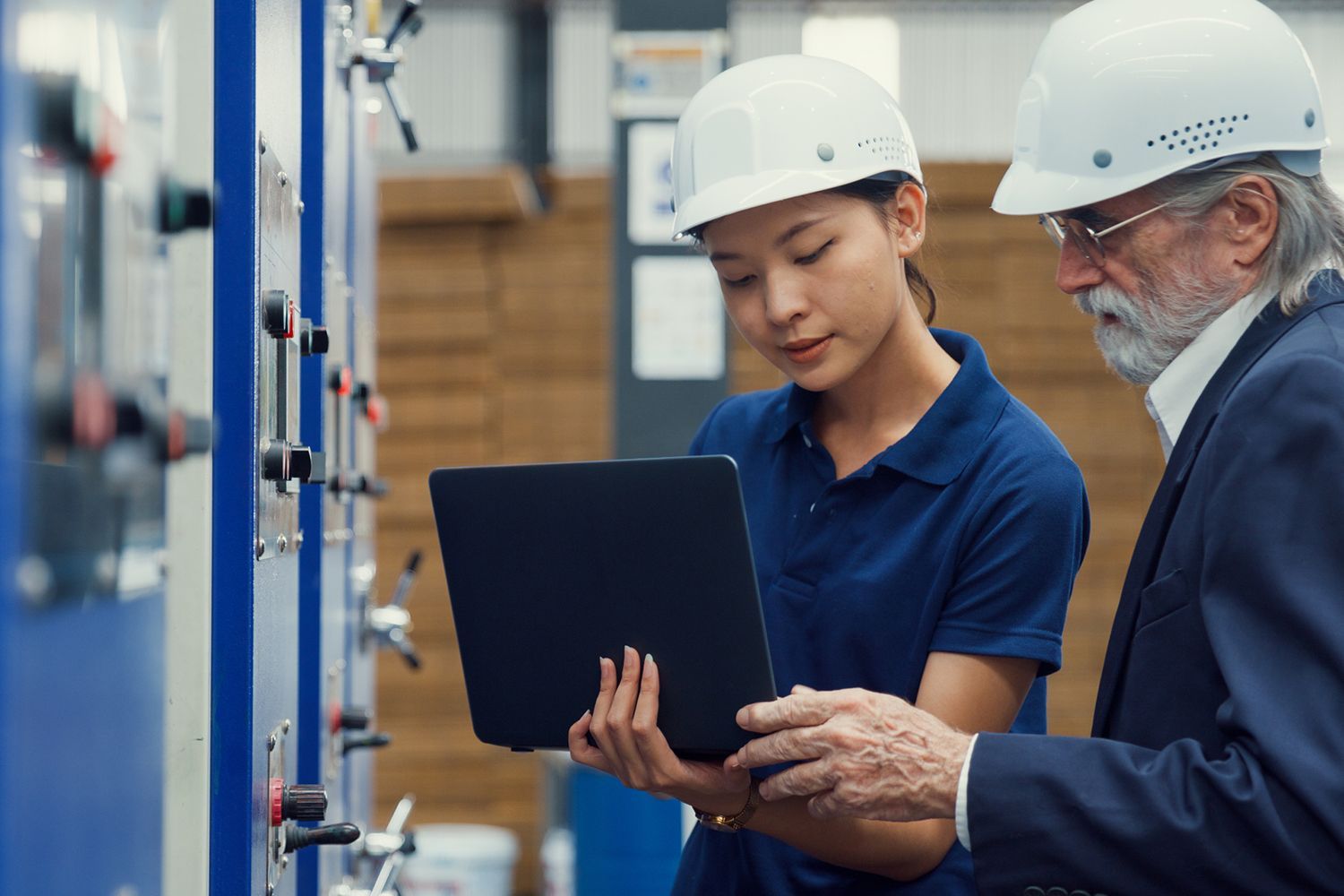 A man and a woman are looking at a tablet in a factory.