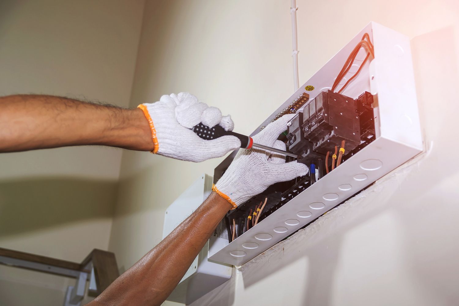A man is fixing an electrical box with a screwdriver.