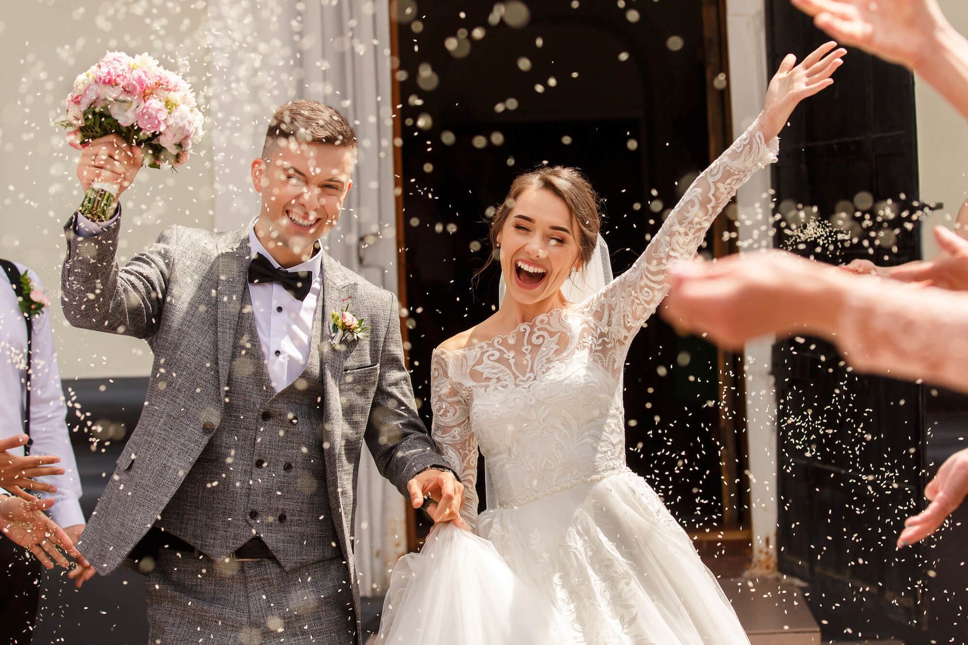 A bride and groom are being showered with confetti by their wedding guests.