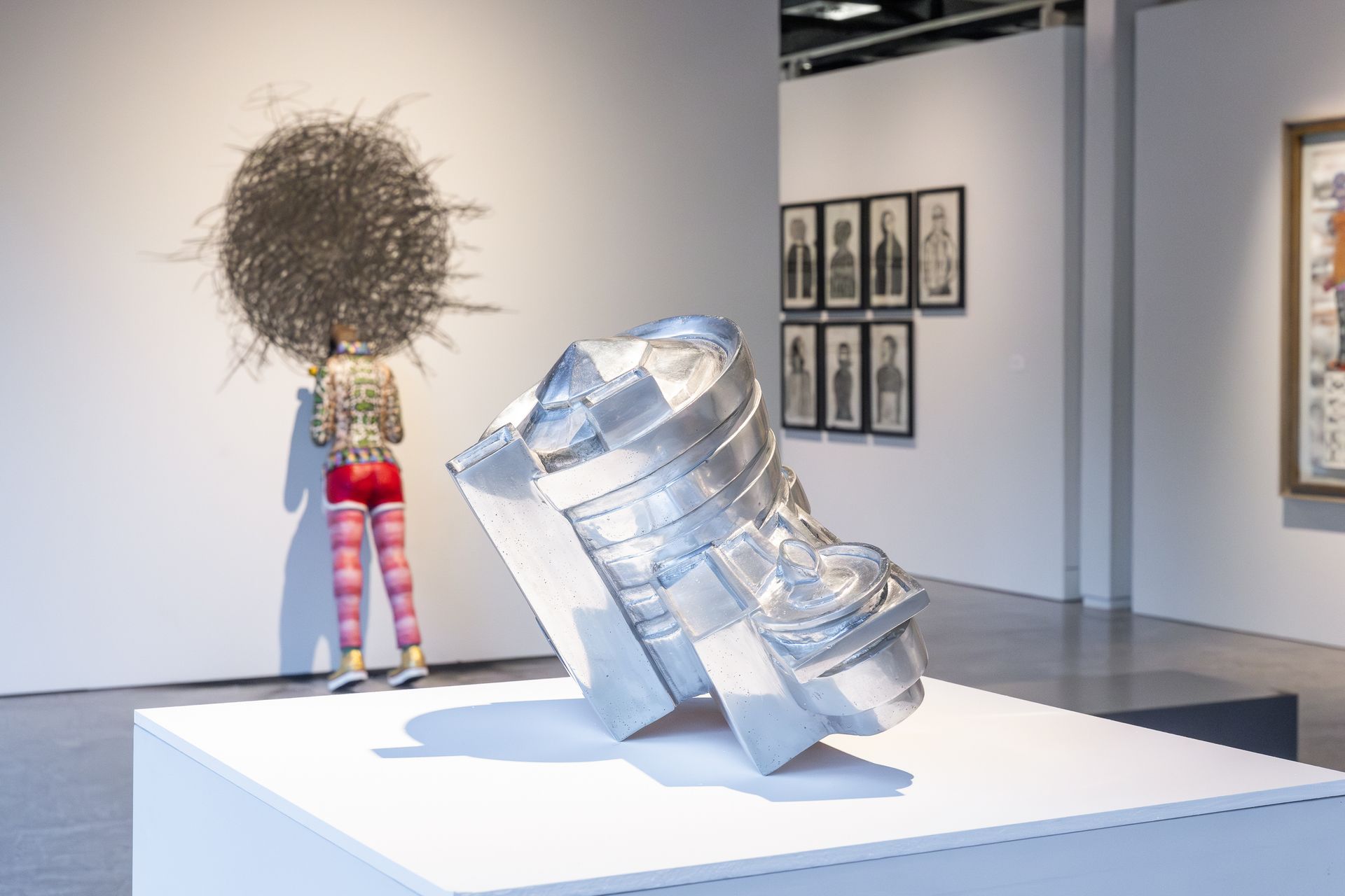 Una mujer está parada frente a una escultura en un museo.