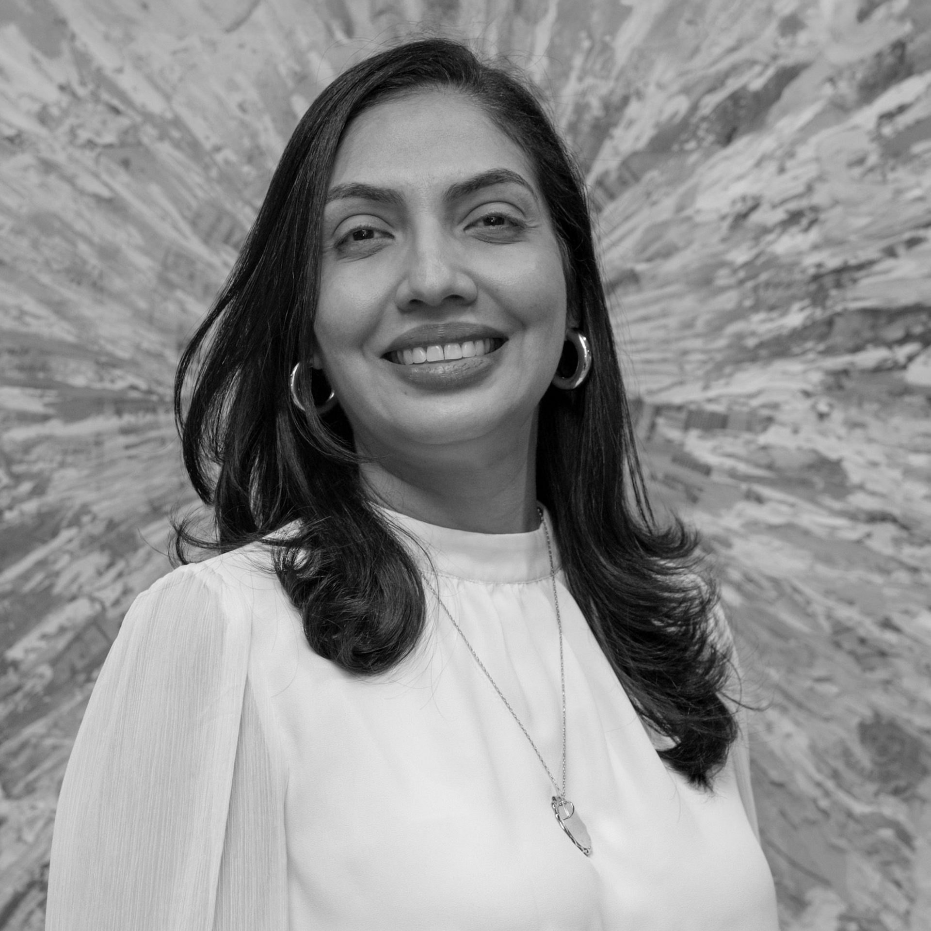 Una mujer que lleva gafas sonríe en una foto en blanco y negro.