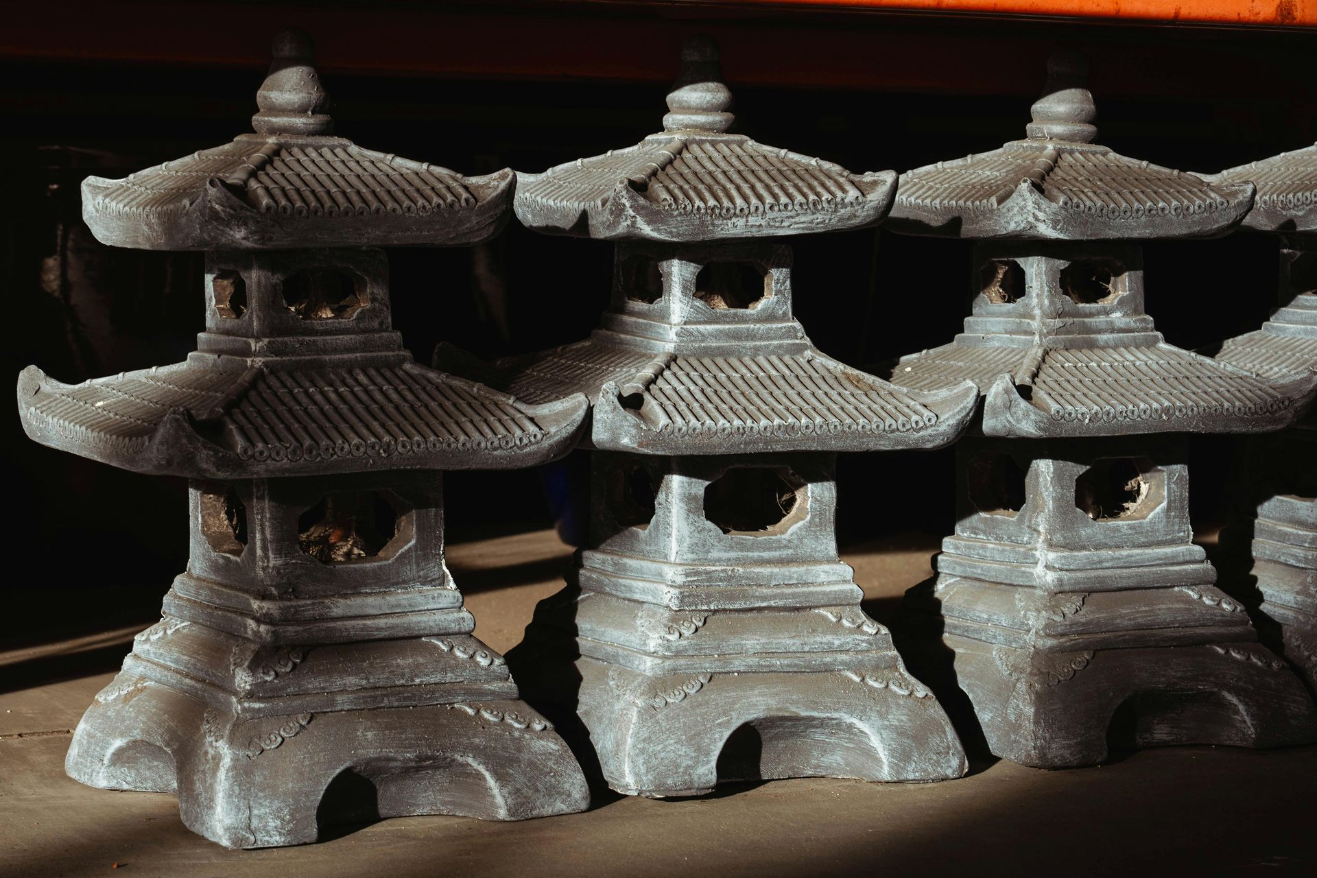 Row of gray stone Japanese garden lanterns with multi-tiered structures.