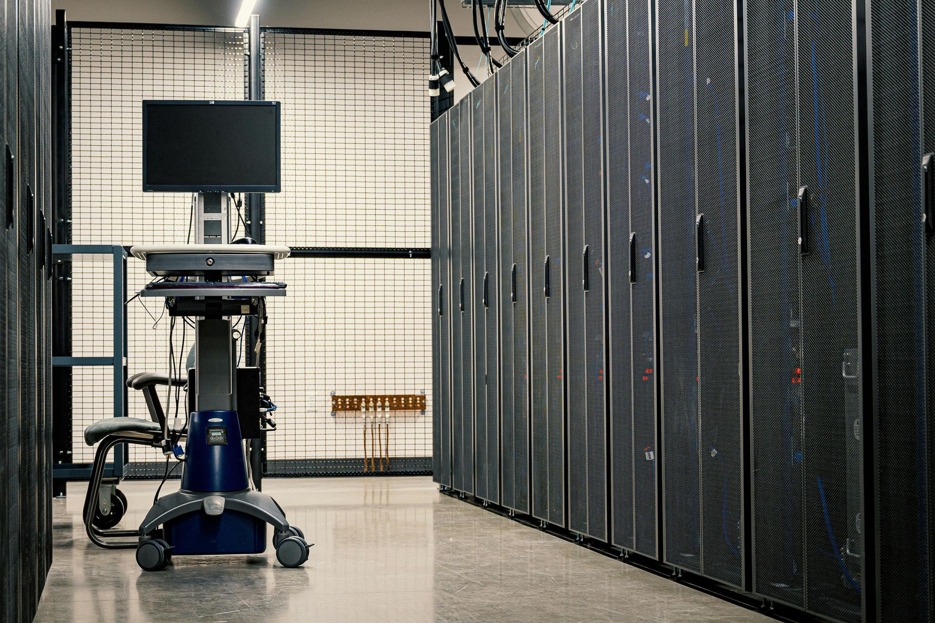 Rows of server racks in a data center, with a mobile workstation in the foreground.