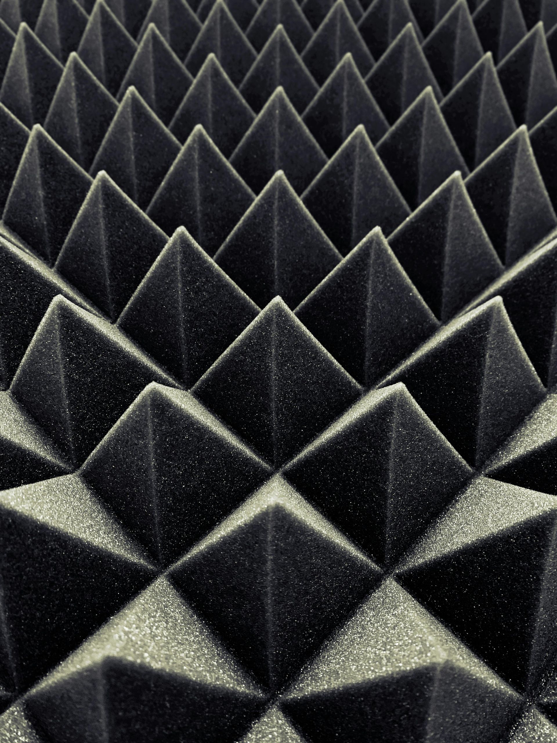Dark gray soundproofing foam in a repeating pyramid pattern.