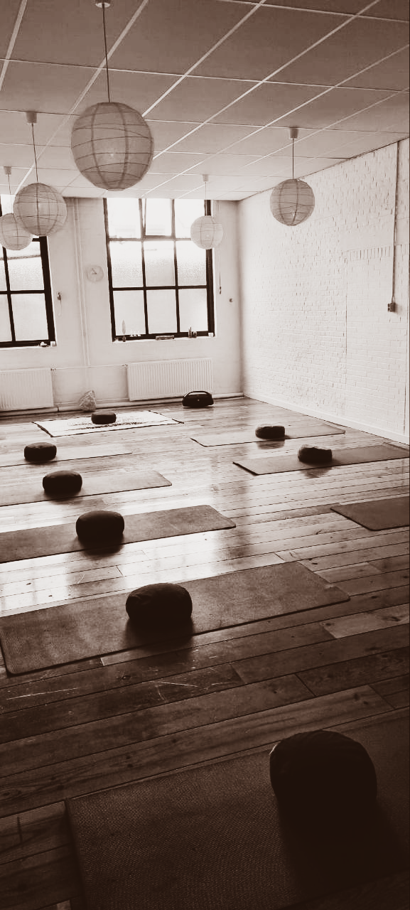 Yogastudio met matten, ronde kussens en papieren lantaarns.