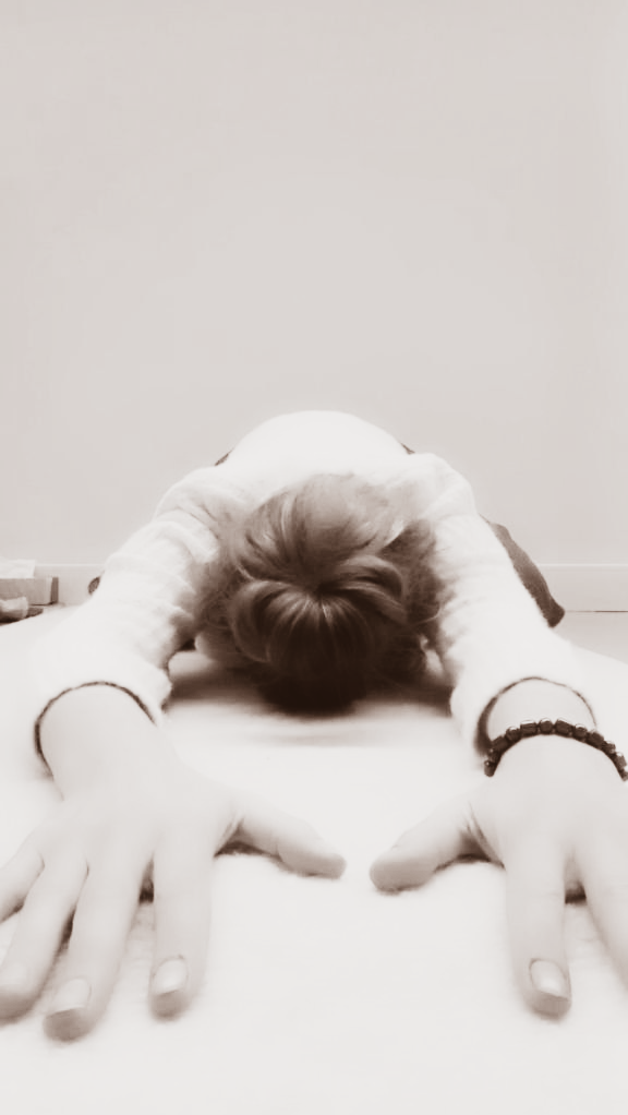 Persoon in de kindhouding (yoga), armen gestrekt, voorhoofd op de mat, lichte huidskleur.