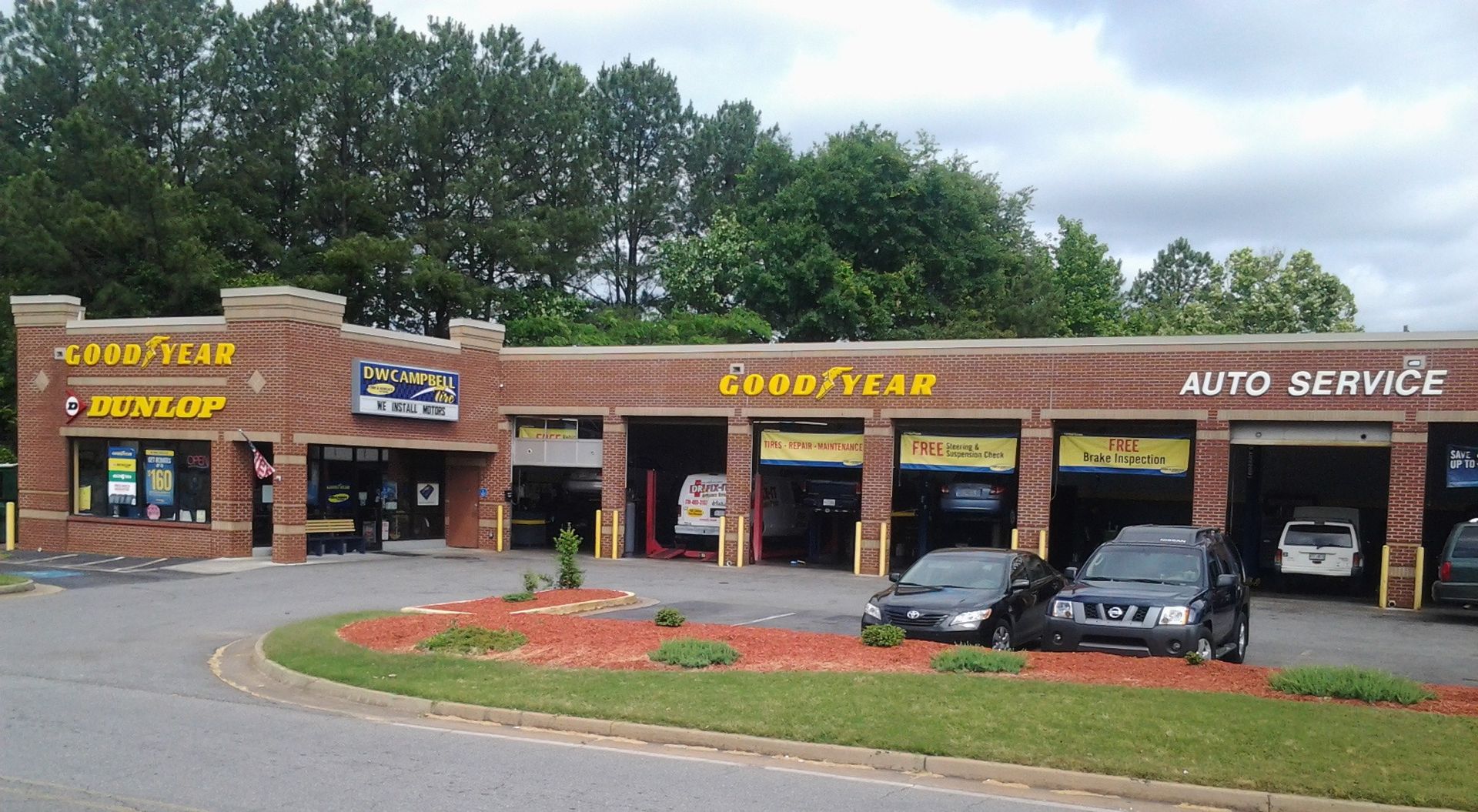 D.W. Campbell Tire shop with brick facade, cars being serviced, and a curved driveway.