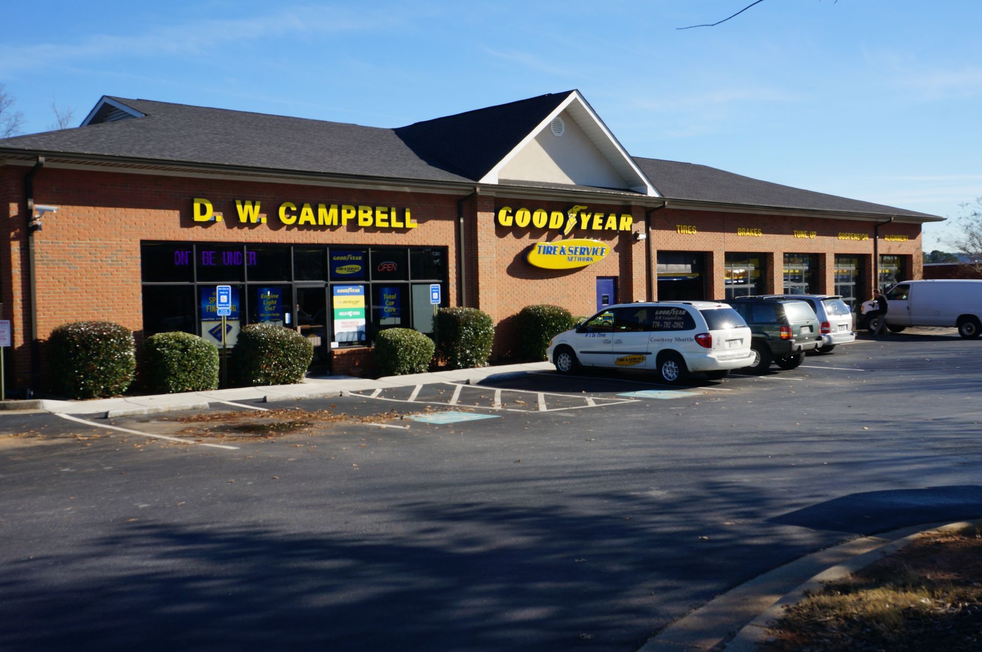 D.W. Campbell tire shop in a brick building on a sunny day, with cars parked out front.