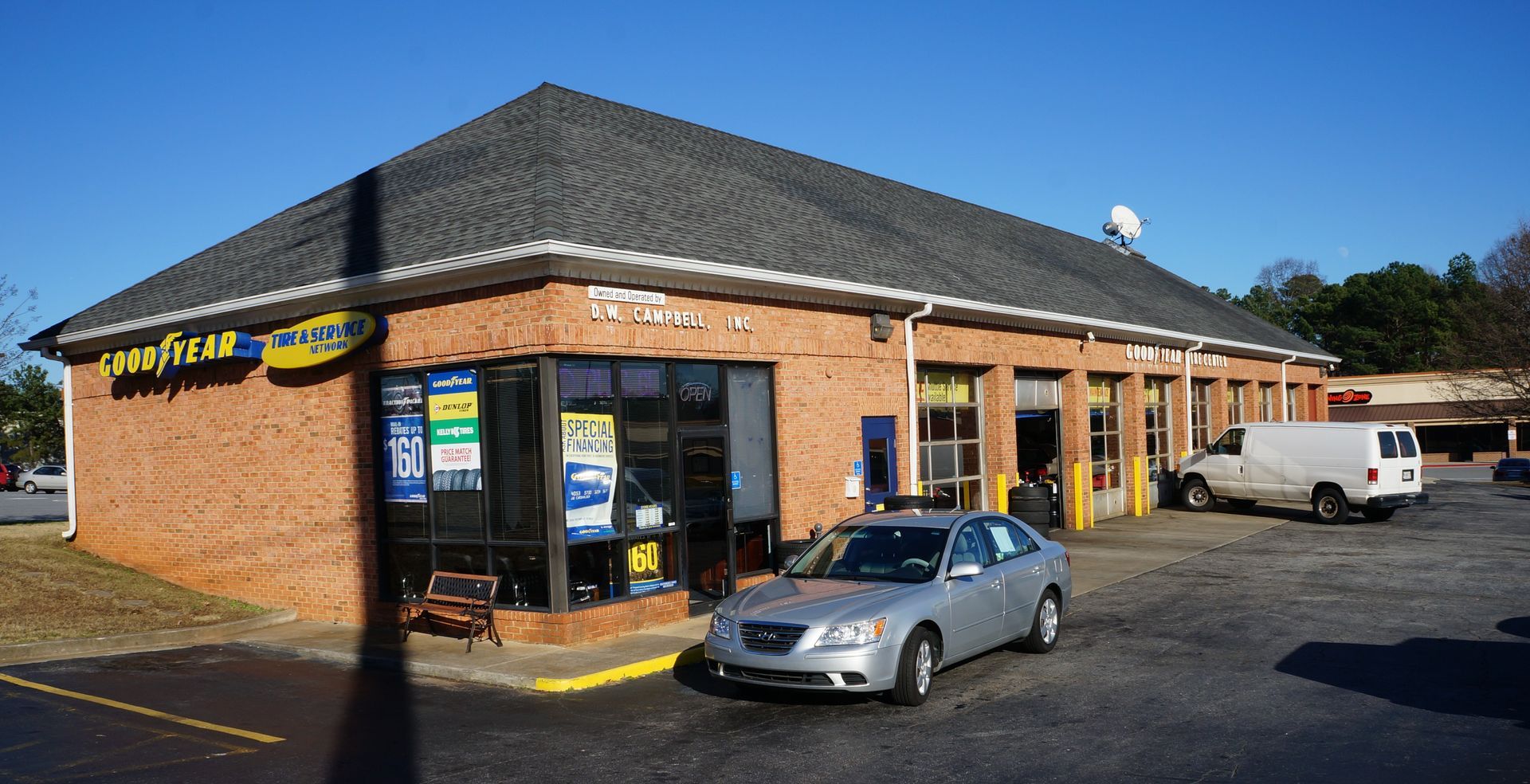 D.W. Campbell Tire shop with a car parked out front and a white van in the lot.
