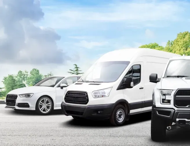Row of three white fleet vehicles parked outside | D.W. Campbell Tire & Service