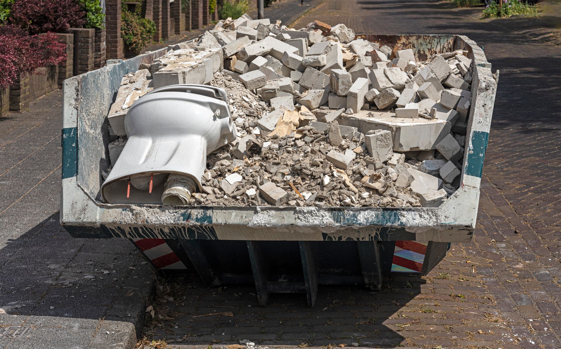 Un cassonetto traboccante di detriti edili, tra cui un water.