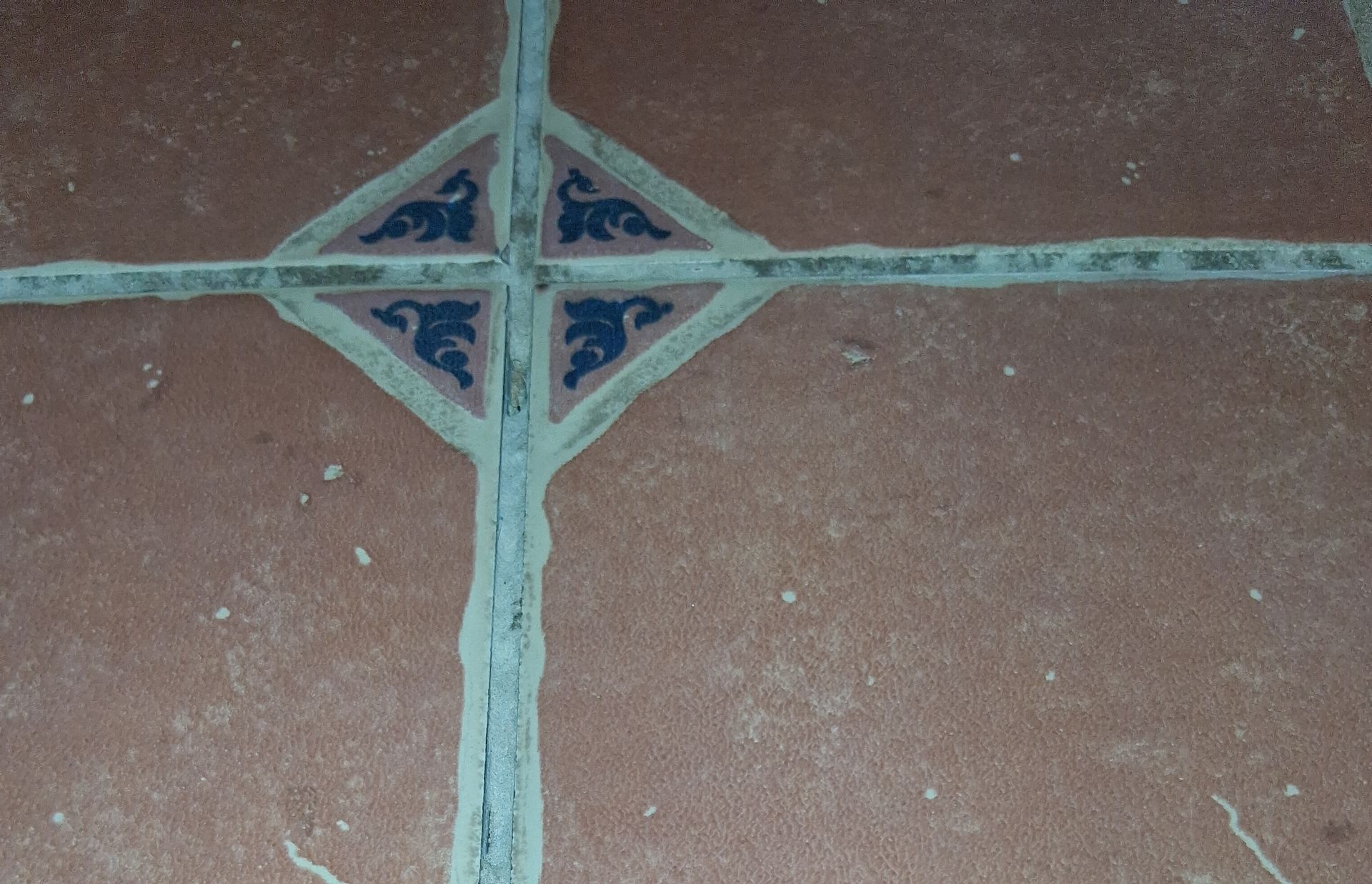 Beige tiled kitchen floor between wooden cabinets.