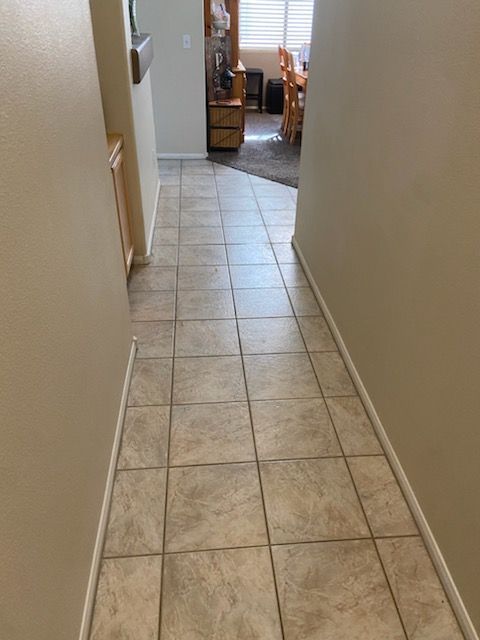 A hallway with tile floors leading to a living room and dining room.