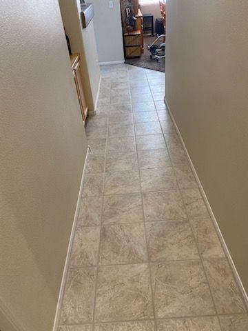 A hallway with tile floors leading to a living room.