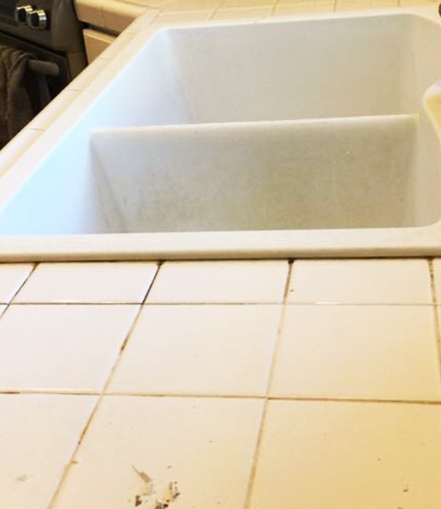 A kitchen sink is sitting on a tiled counter top