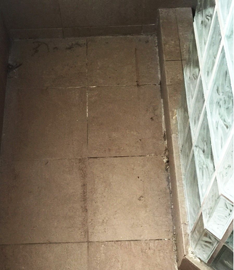 A tiled floor next to a glass block wall