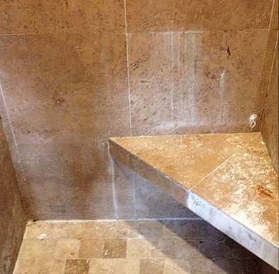 There is a corner bench in the shower.