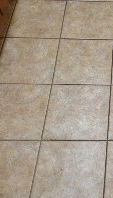 A close up of a tiled floor with a wooden cabinet in the background.