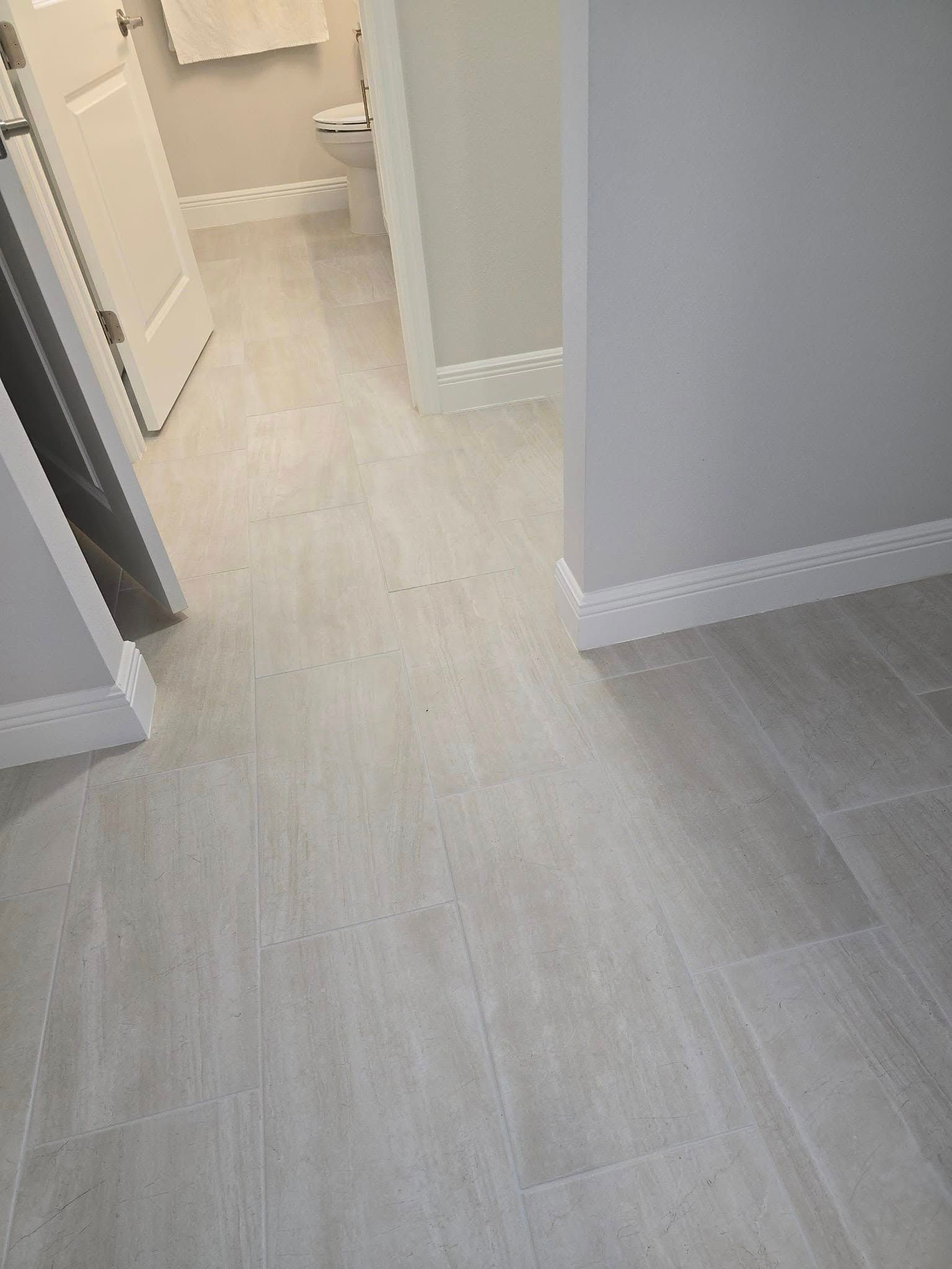 A bathroom with a white tile floor and a toilet.
