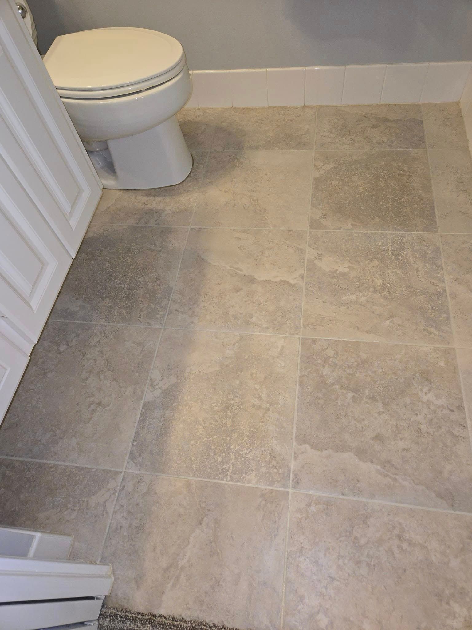 A bathroom with a toilet and a tiled floor.