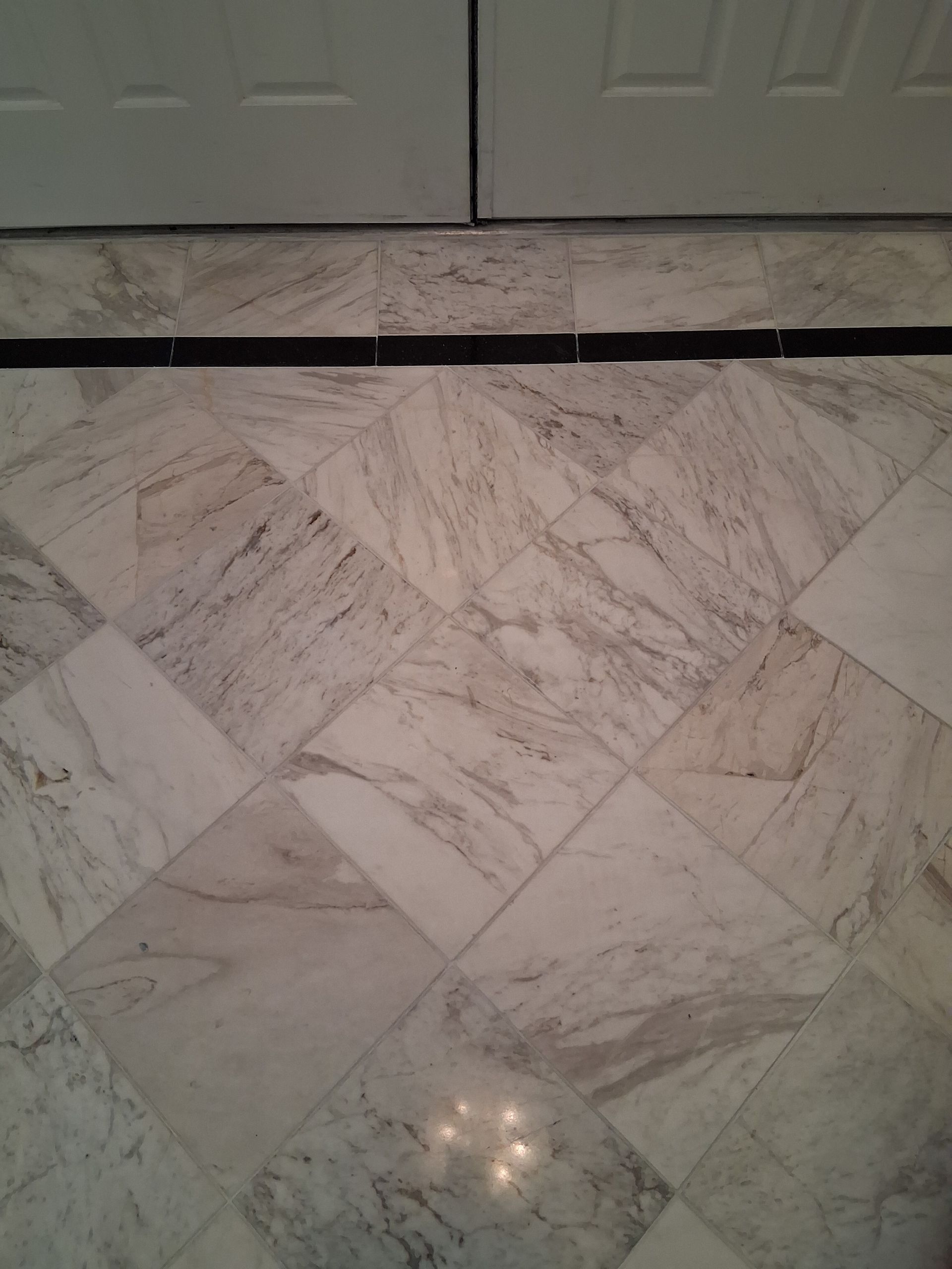 A hallway with tile floors leading to a living room.