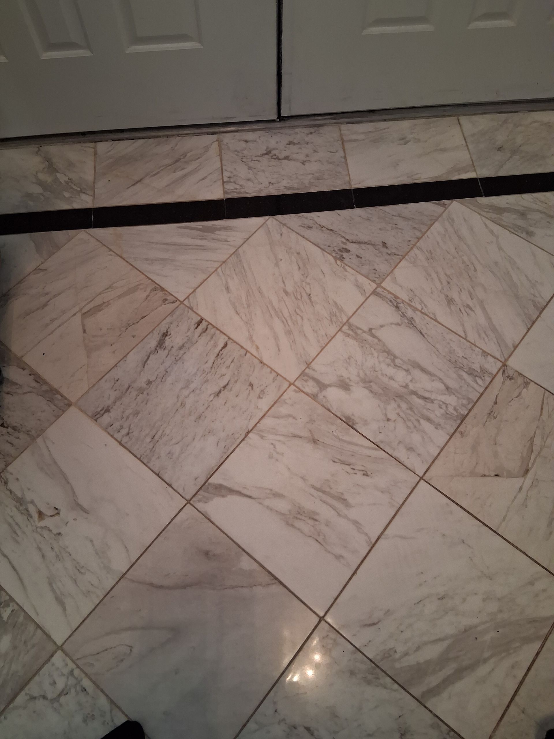 A hallway with tile floors leading to a living room and dining room.