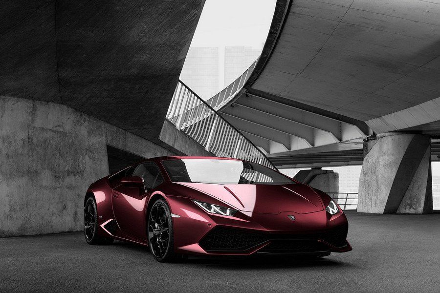 Red Lamborghini sports car parked under a concrete overpass.