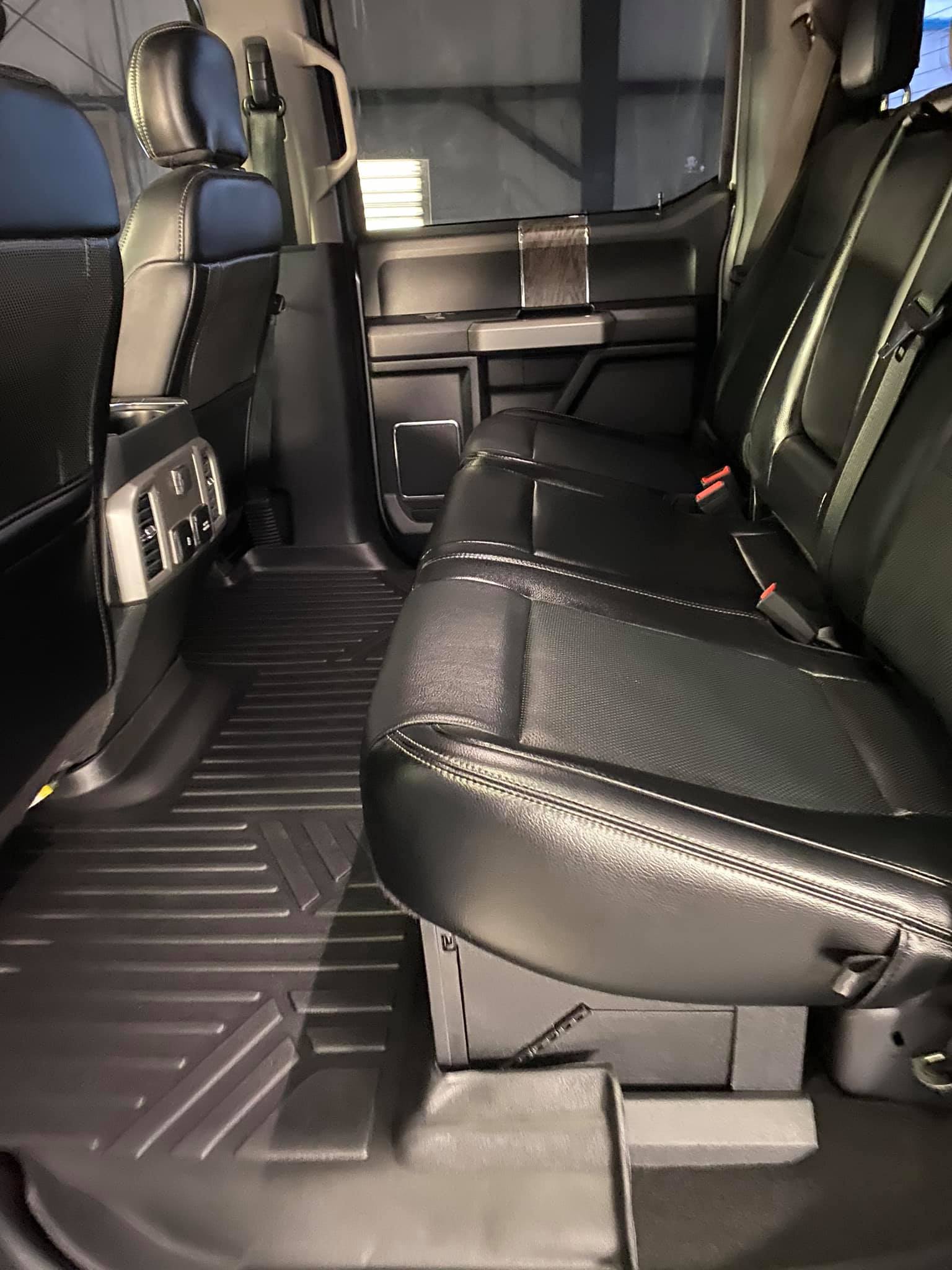 Black leather truck backseat with floor mats.
