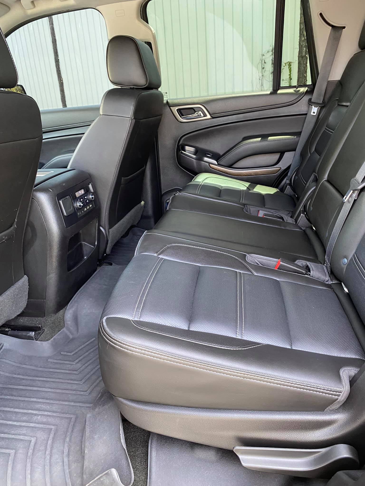 Rear interior of a black SUV with leather seats and gray floor mats.