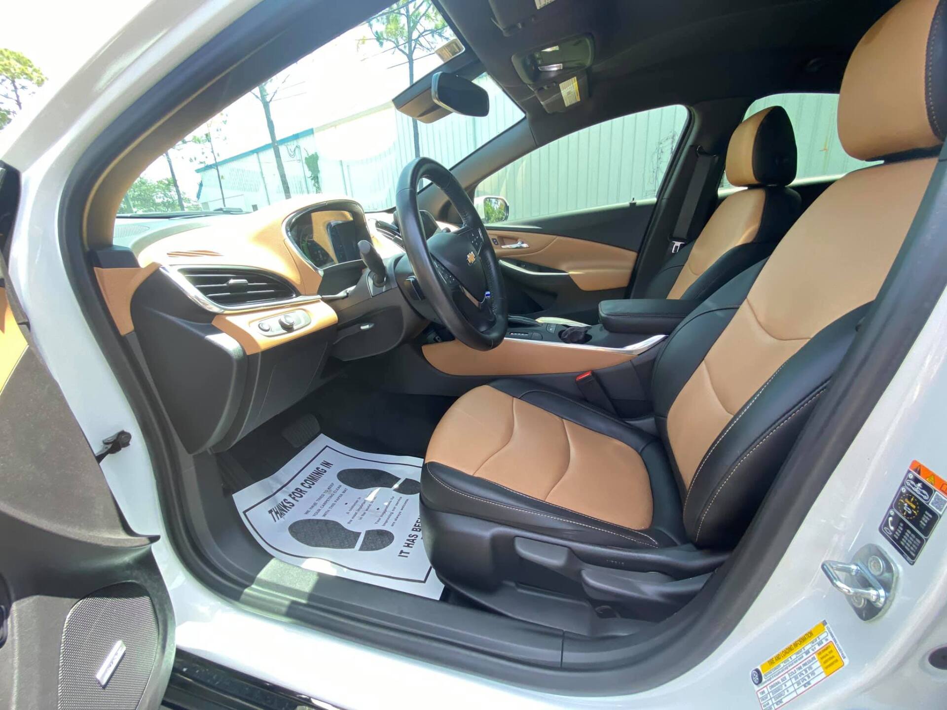 Interior of a white car with black and tan leather seats, steering wheel, and dashboard.