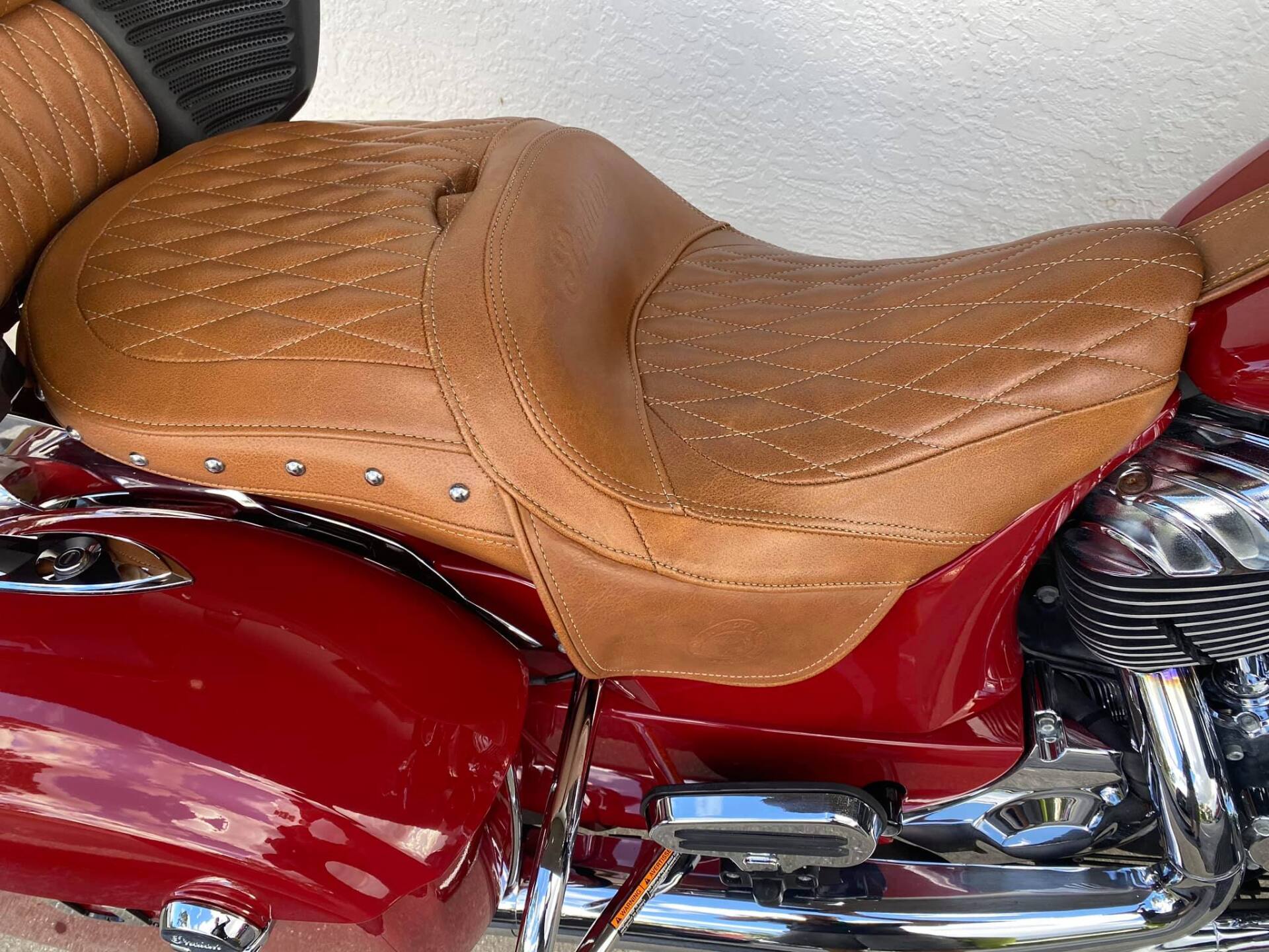 Brown leather motorcycle seat on a red motorcycle.