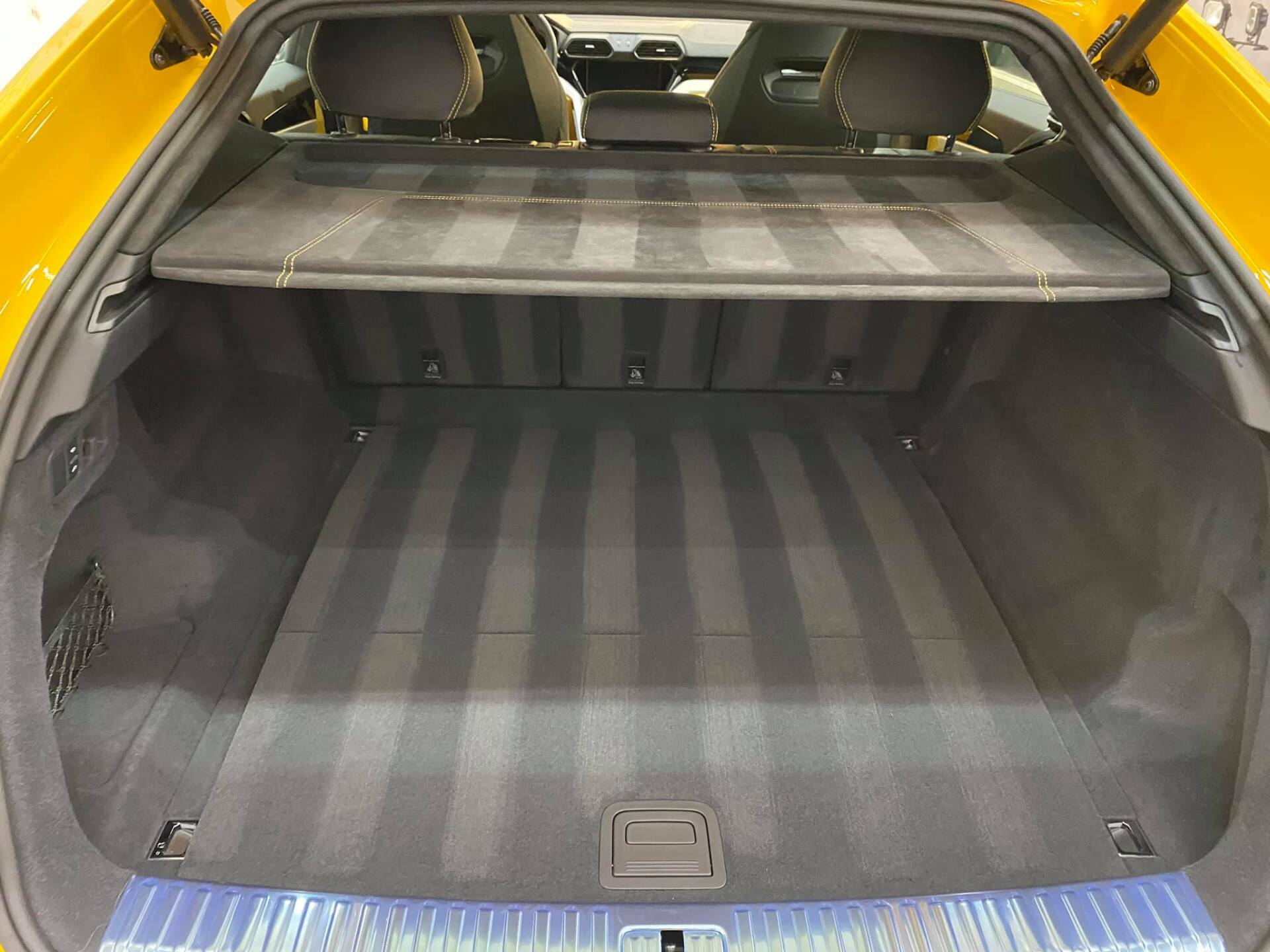 Yellow car trunk, empty with black carpet, showing grooves.