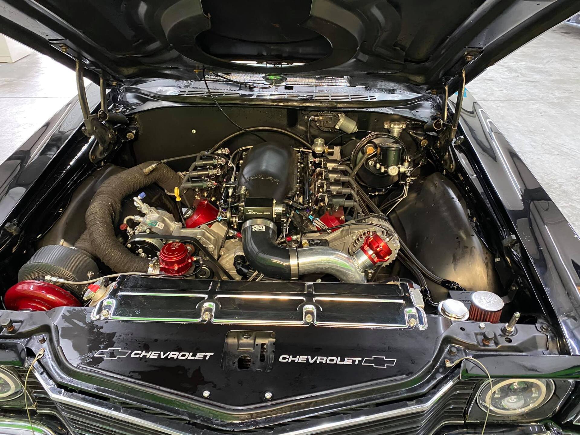 Black classic car engine bay, modified with red accents and exposed components.