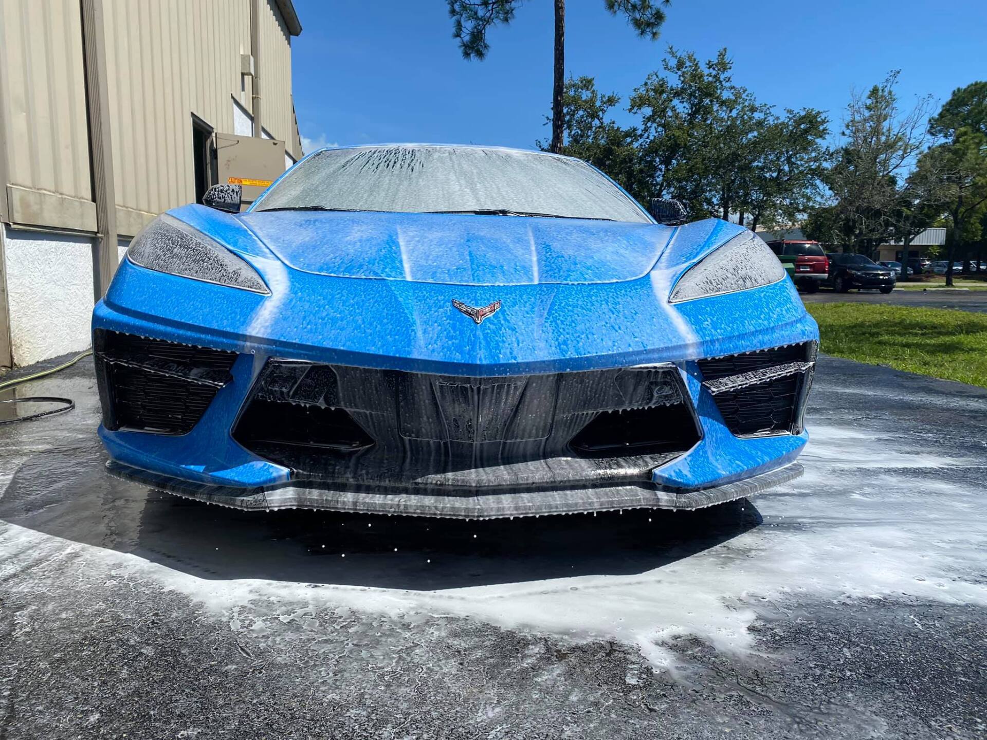 Blue Corvette covered in white foam at a car wash.