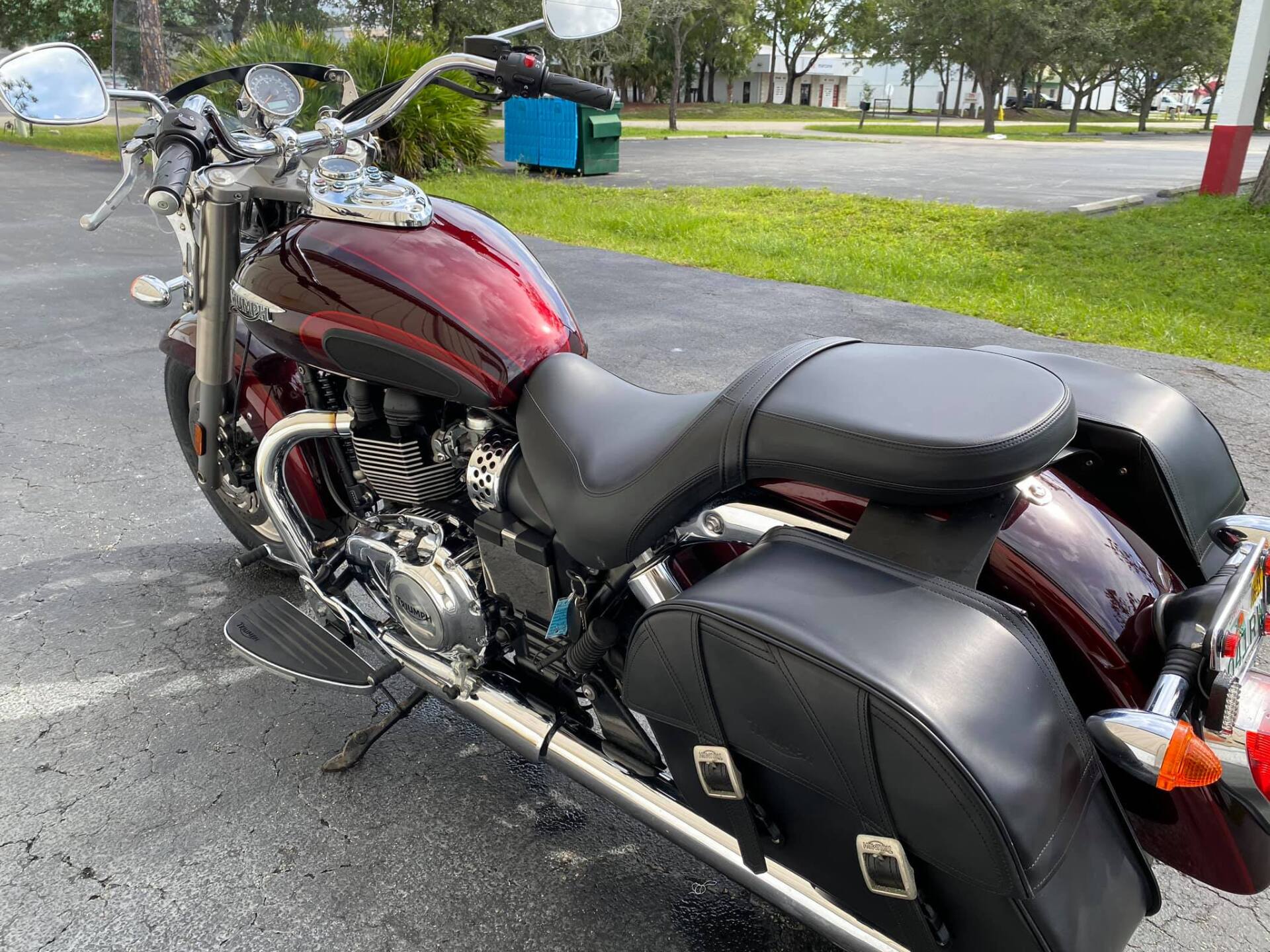 Maroon and chrome motorcycle with black saddlebags parked on asphalt.