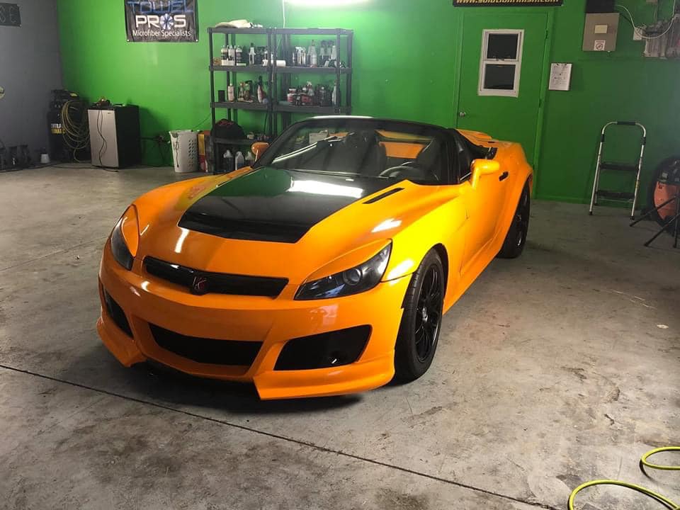 Yellow and black sports car inside a garage with green walls.