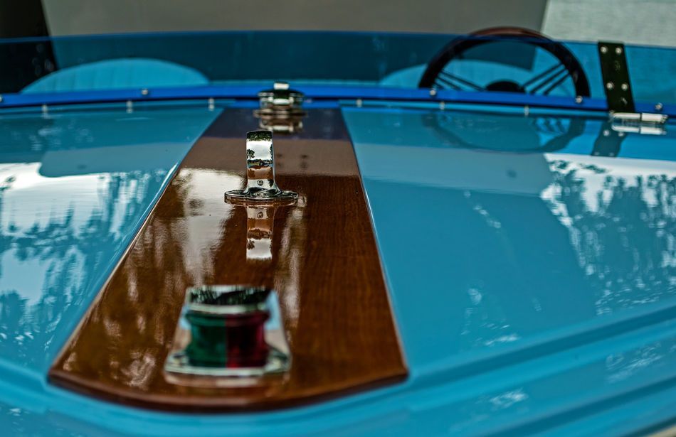 Close-up of a blue wooden boat's bow with a polished wooden strip and navigation lights.