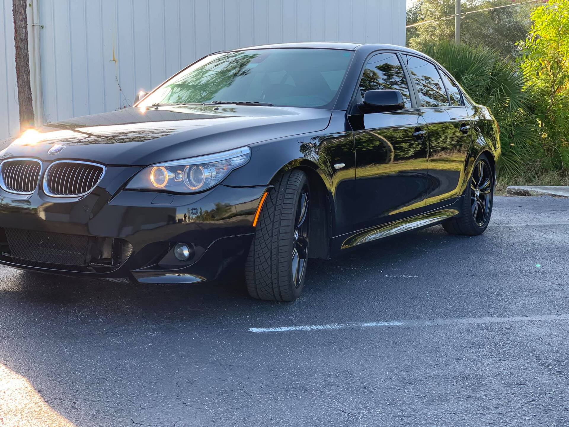 Black BMW sedan parked on asphalt, with sunlight on the front.