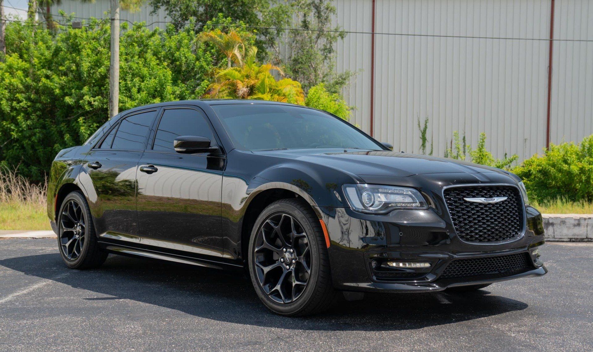 Black Chrysler 300 sedan parked outside; black wheels, tinted windows, sunny day.