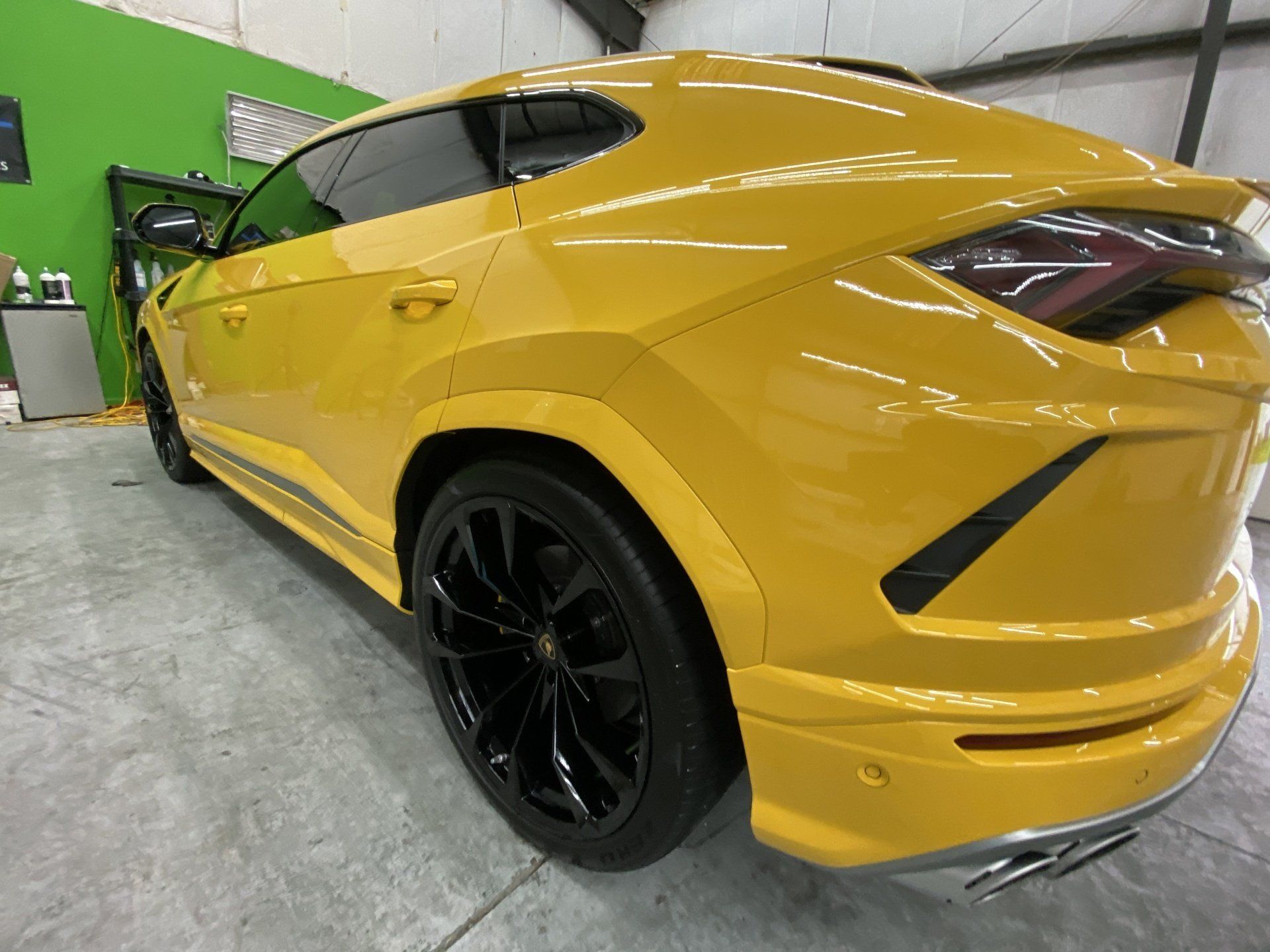 Yellow Lamborghini Urus SUV with black wheels parked indoors.