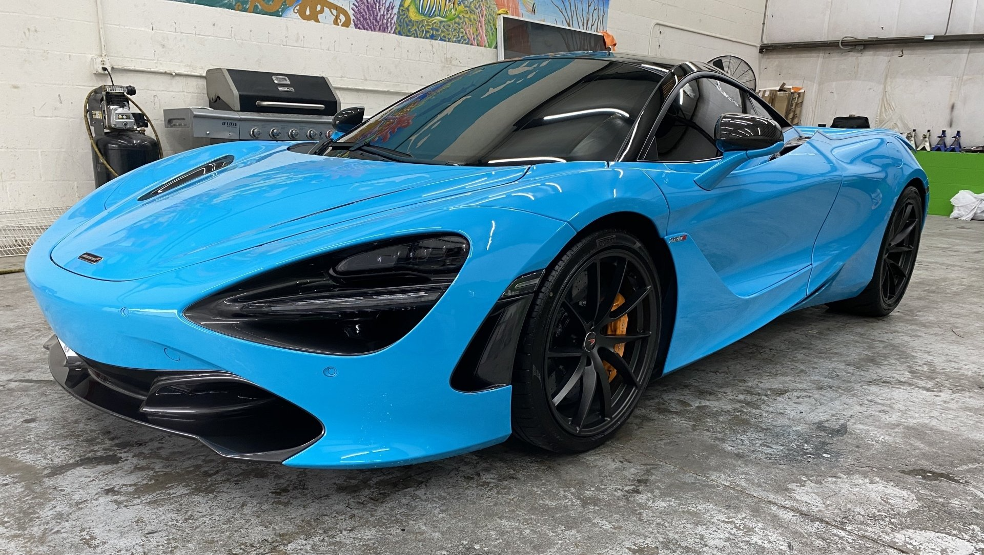 Bright blue McLaren sports car parked indoors.