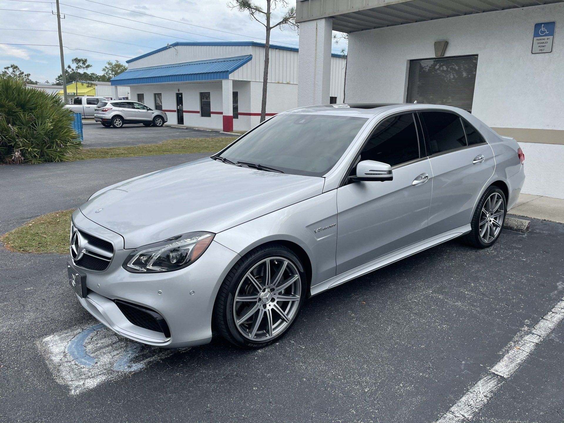 Silver Mercedes-Benz sedan parked outside a building, featuring tinted windows and dark wheels.