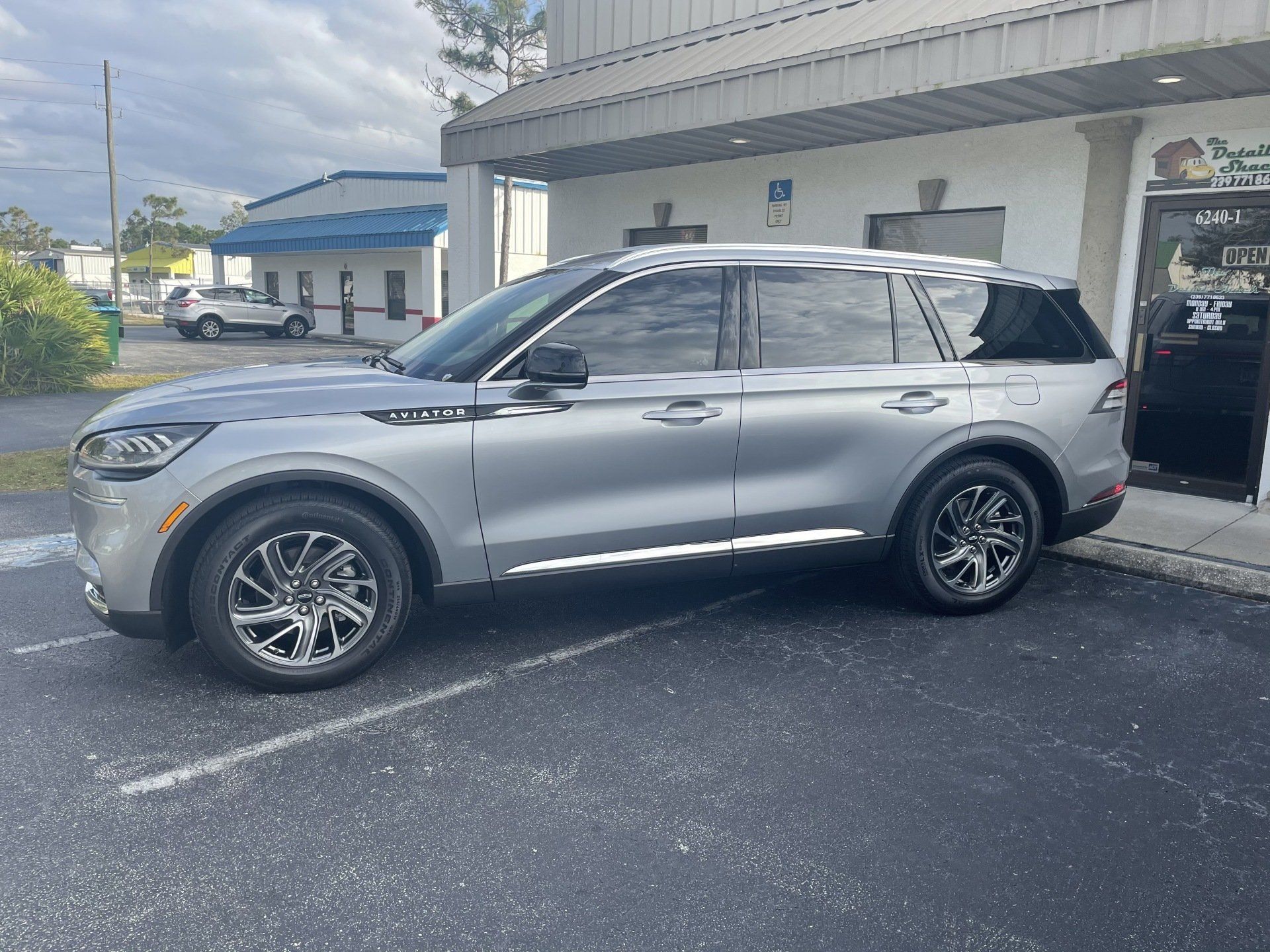 Silver Lincoln Aviator SUV parked in front of a building with tinted windows.