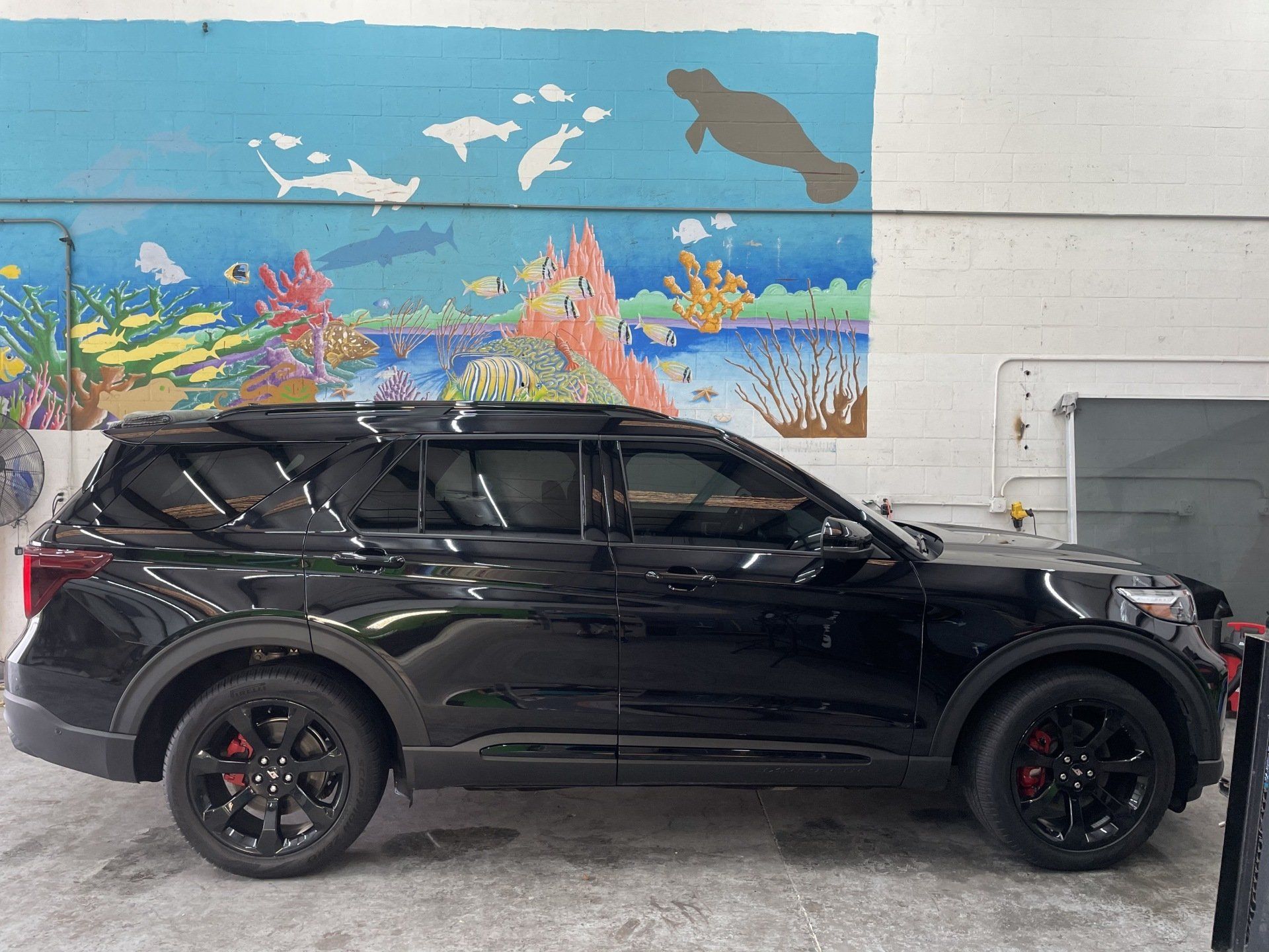 Black SUV parked in front of a wall mural depicting an underwater scene with sea life.