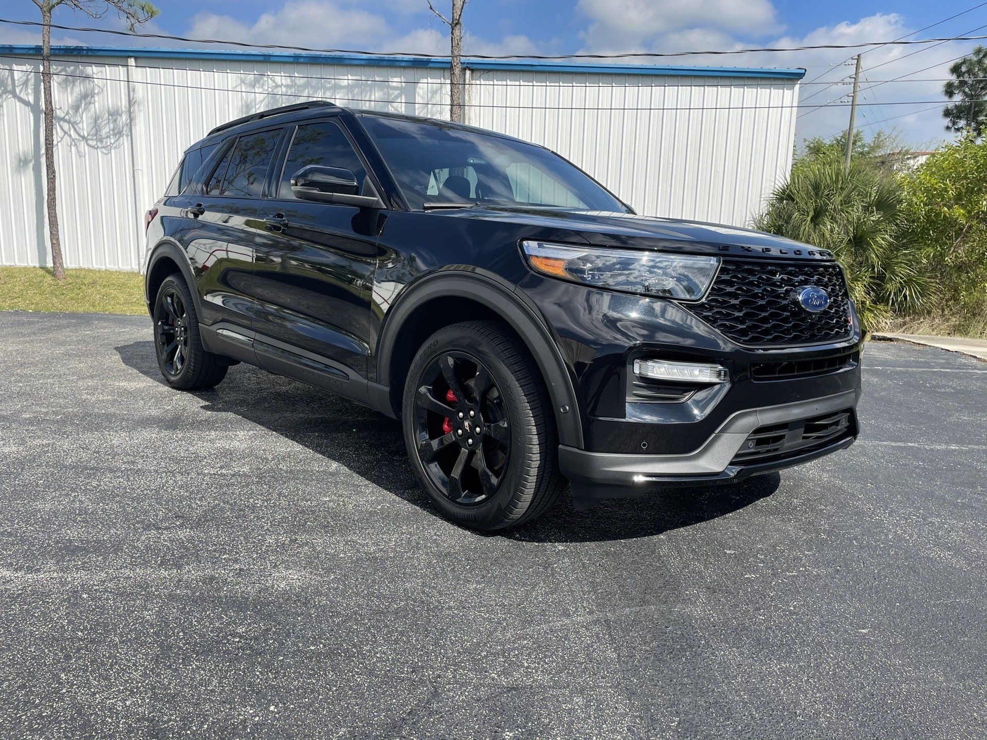 Black Ford Explorer SUV parked on asphalt in front of a white building.