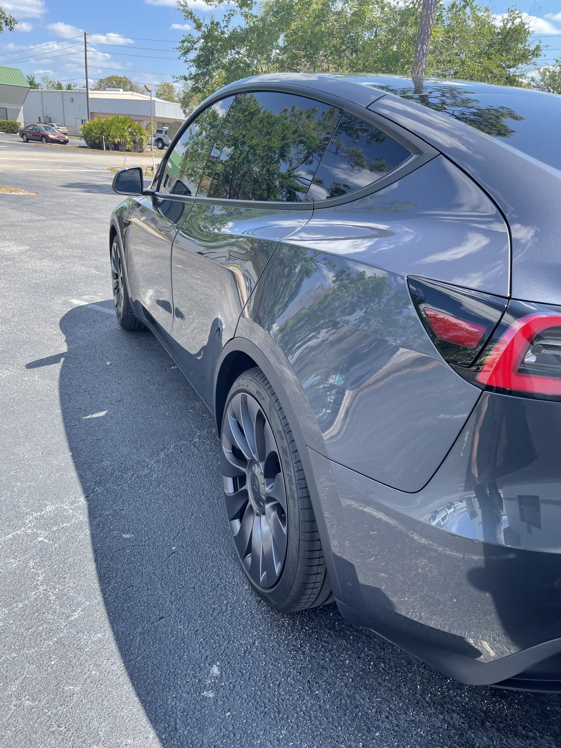 Dark gray Tesla Model Y parked on asphalt, sunny day.