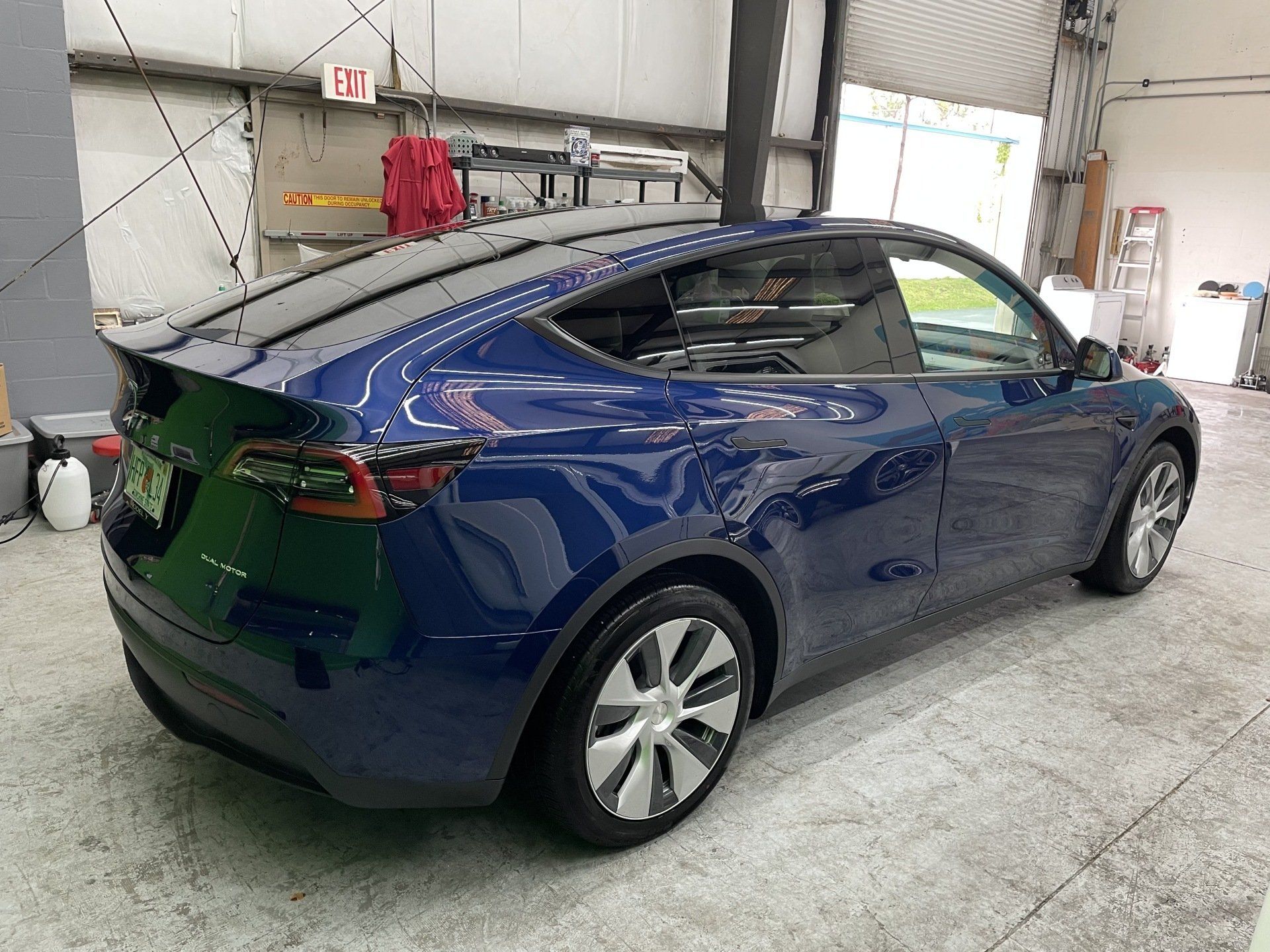 Blue Tesla Model Y in a garage, angled view.