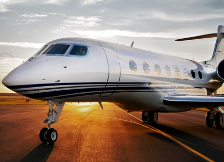 White private jet on a runway at sunset.