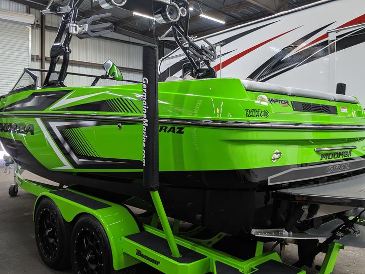 Bright green wake boat on a matching trailer. Features black accents and a tower.