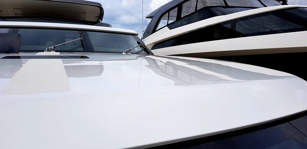 White car hood reflecting sky and boat.